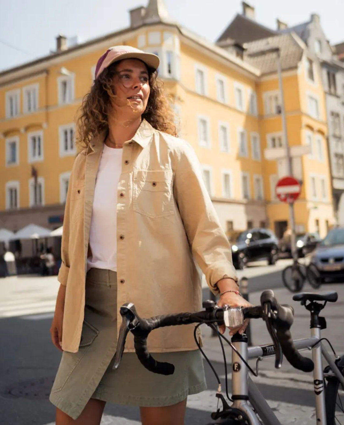 Elevenate Utility Shirt i safari beige bärs som överskjorta utomhus med cykel i stadsmiljö.