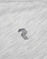 Närbild på det gråmelerade tyget med en broderad Peak Performance-logotyp.