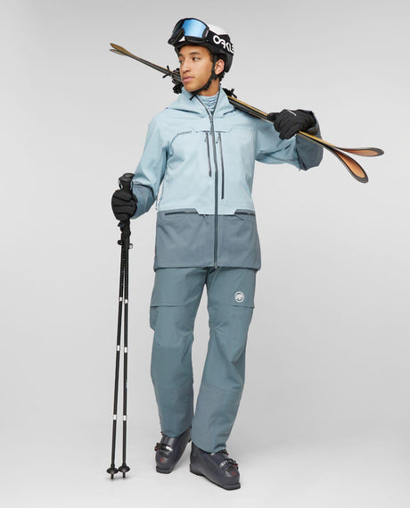 Skidåkare i Mammut Haldigrat HS Hooded Jacket i färgen Nebla-Strata med skidor på axeln i studion.