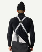 Bakifrånvyn av en person som bär Houdini Rollercoaster Bib Pants II i svart med grå hängslen och en dragkedja öppen i ryggen.