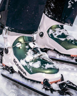 Scarpa F1 RS Women toppturspjäxor i vitt och grönt med snö i vintermiljö