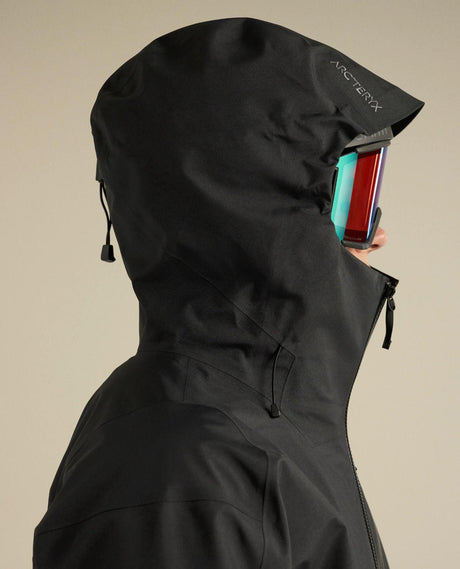 Arc'teryx Sabre Jacket Men i svart med fokus på hjälmkompatibel StormHood och skidglasögon.