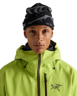 Modell som bär Arc'teryx Grotto Toque i svart och grått tillsammans med en limegrön skidjacka.