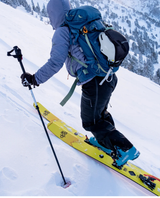 En person på topptur med gula DPS Pagoda Tour CFL 112 skidor i snöigt bergslandskap.