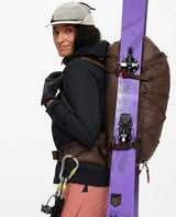 Skidåkare med Klättermusen Gyme Backpack 25L i färgen Slate Brown med skidor fästa på säcken.