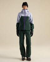 Arc'teryx Rush Bib Pant dam i färgen Dark Jade, visad med skidjacka och skidutrustning för friåkning.