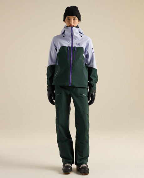 Arc'teryx Rush Bib Pant dam i färgen Dark Jade, visad med skidjacka och skidutrustning för friåkning.